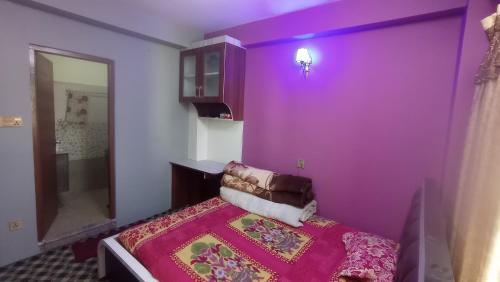 a purple room with a bed and a mirror at Chandragiri Apartment in Khokna