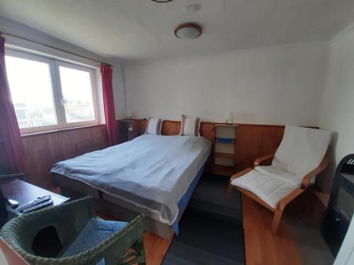 um pequeno quarto com uma cama e uma cadeira em Házikó a Duna-parton em Ráckeve