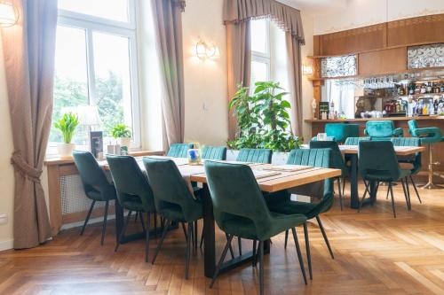 a dining room with a table and green chairs at Sztuka Smaku - Restauracja i Hotelik in Świdnica