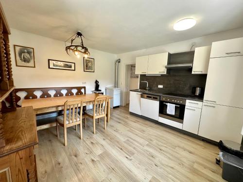 a kitchen with white cabinets and a wooden table at Salzkammergut Homes Gmunden - Haus im Grünen, Ruhe, großer eingezäunter Garten - ideal für Familien und Hunde in Pinsdorf