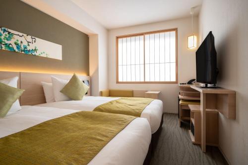 a hotel room with two beds and a flat screen tv at Hotel Vista Premio Kyoto Nagomi tei in Kyoto