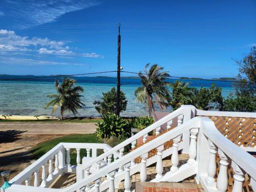 uma escada branca que leva a uma praia com o oceano em Villa Angélique 