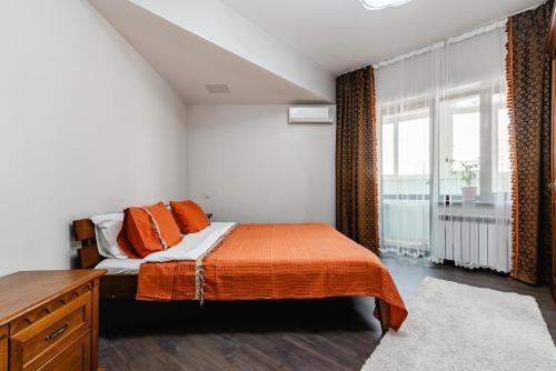 a bedroom with a bed with orange sheets and a window at Aray apartment in Almaty