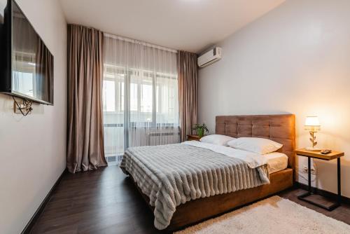 a bedroom with a bed and a large window at Aray apartment in Almaty