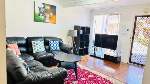 a living room with a leather couch and a table at Quiet family Townhouse in Wollongong CBD in Wollongong