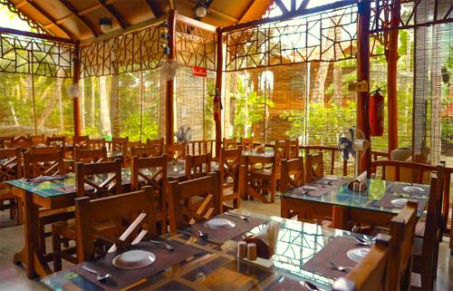 uma sala de jantar com mesas, cadeiras e janelas em Havelock Island Beach Resort em Ilha Havelock