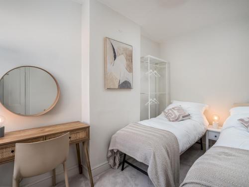 a bedroom with two beds and a desk and a mirror at Pass the Keys Stunning 3 Bedroom Townhouse in Central St Albans in St. Albans