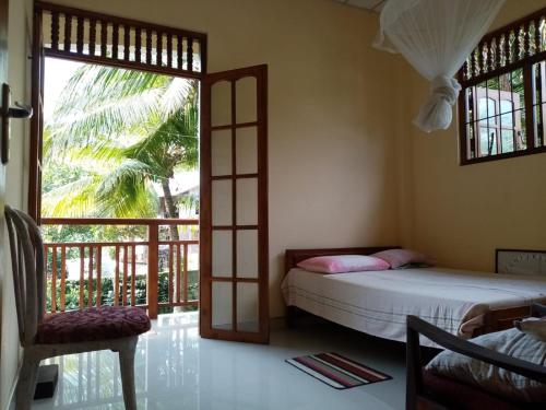 um quarto com uma cama, uma janela e uma cadeira em OM SHAMBALA Yoga Ashram em Anuradhapura