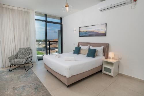 1 dormitorio con 1 cama, 1 silla y 1 ventana en Hi-Yam SeaView Apartments & Suites - יש ממ"ד, en Bat Yam