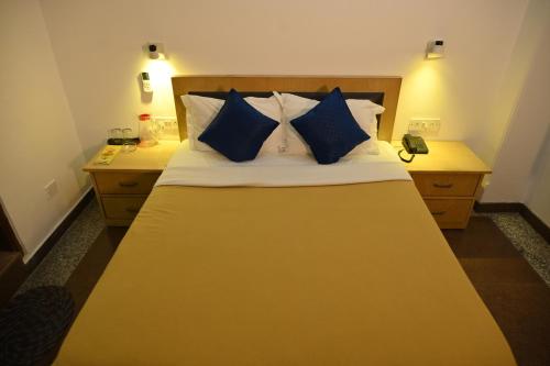 a bedroom with a large bed with blue pillows at Hotel DH in Dharamshala