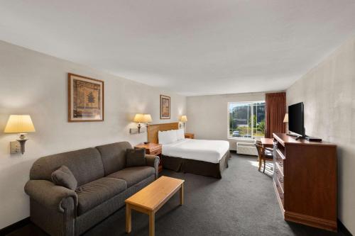 Rodeway Inn & Suites Tomahawk في توماهوك: غرفة في الفندق مع أريكة وسرير