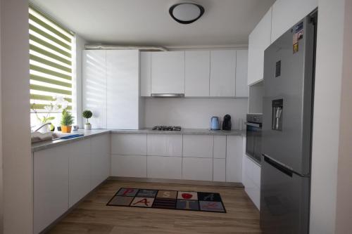 una cucina con armadi bianchi e frigorifero in acciaio inossidabile di Panorama Luxury Apartment a Oradea
