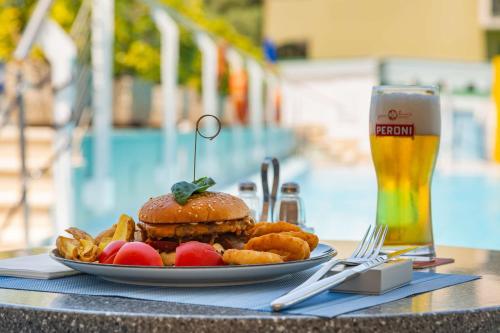 a plate with a hamburger and french fries and a glass of beer at Best Western Hotel La Solara in Sorrento
