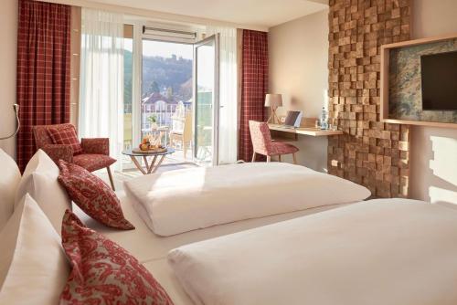 um quarto de hotel com duas camas e uma varanda em Dorint Resort & Spa Bad Brückenau em Staatsbad Brückenau