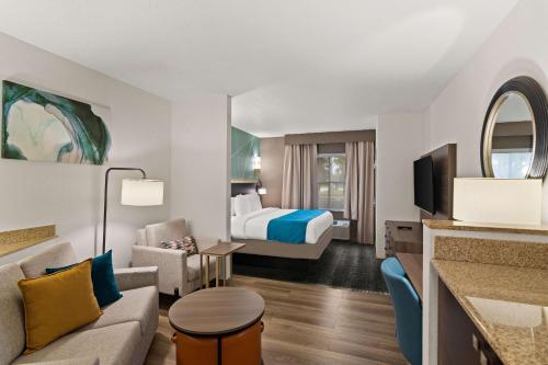 Habitación de hotel con cama extragrande y sala de estar. en Comfort Suites Vero Beach I-95 en Vero Beach