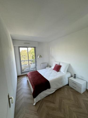 a white bedroom with a bed and a window at Appartement neuf avec balcon et parking privé in Caen