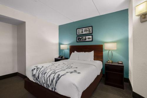 a hotel room with a bed and a blue wall at Sleep Inn in Wilmington