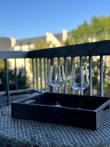 trois verres à vin dans un porte-vin noir sur une table dans l'établissement Appartement neuf avec balcon et parking privé, à Caen