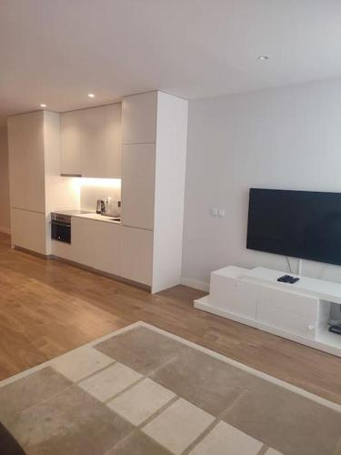a living room with a television and a white kitchen at Terro Collection - São Vicente 78 in Braga