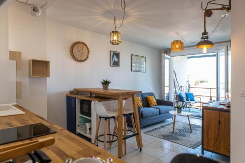 Il comprend une cuisine et un salon avec une table et un canapé bleu. dans l'établissement Le Cèdre du Bassin - Au cœur de la Teste, à La Teste-de-Buch