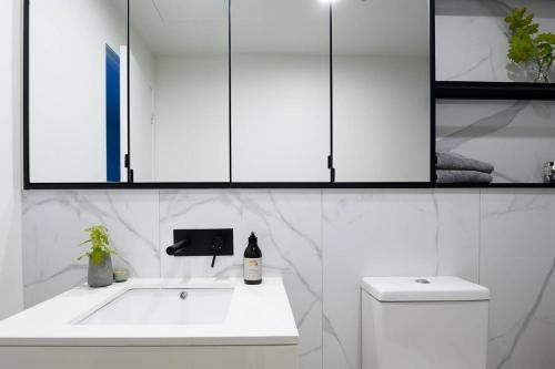 a white bathroom with a sink and a toilet at Luxury Living, Richmond in Melbourne