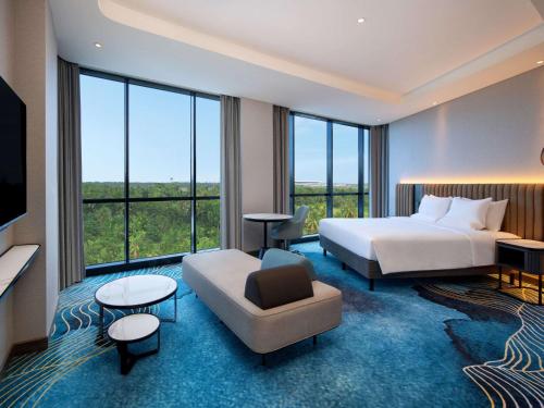 a hotel room with a bed and a couch at Novotel Yogyakarta International Airport Kulon Progo in Yogyakarta