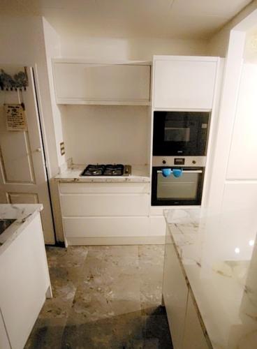 a kitchen with white cabinets and an oven at Deluxe room in Basildon