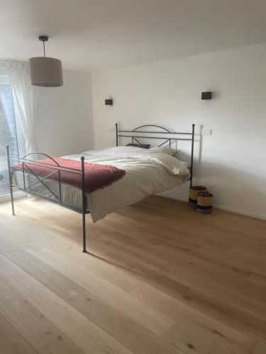 a bed with a metal frame in a room with a wooden floor at Nouvelle construction dans le village de Fays in Theux