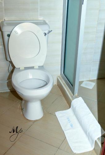a bathroom with a toilet and a towel on the floor at Mei Place Apartments in Mombasa