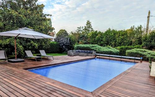 a swimming pool on a wooden deck with an umbrella at Villa Barbizon in Barbizon