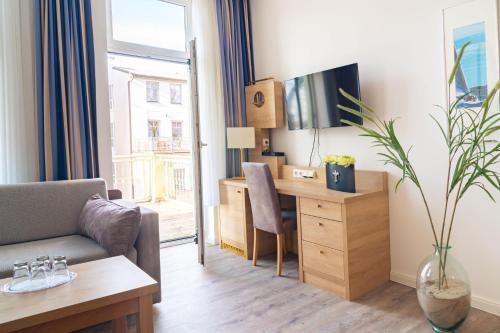a living room with a desk and a tv and a couch at Hanse Appartments II Warnemünde mit Parkplatz in Warnemünde