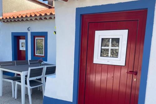 a red door and a table in front of a house at Casa Manuel e Maria in Fátima