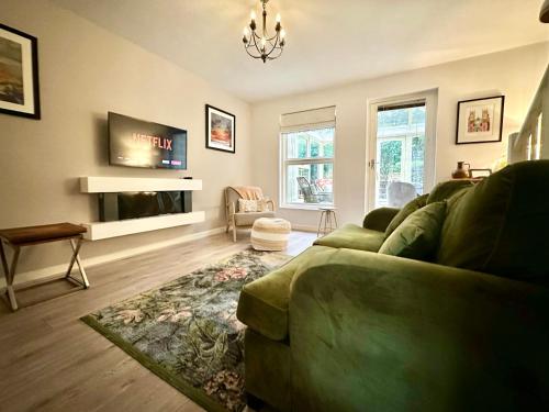 ein Wohnzimmer mit einem grünen Sofa und einem Fernseher in der Unterkunft Cherry Blossom Cottage in York