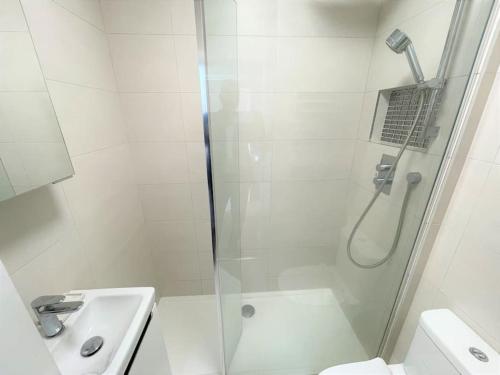 a white bathroom with a shower and a sink at Large South Facing Studio Flat in London