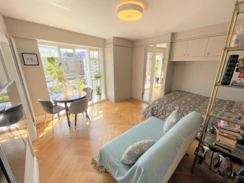 a bedroom with a bed and a table and a dining room at Large South Facing Studio Flat in London