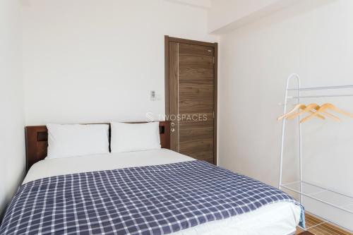 a bedroom with a bed with a blue and white checked blanket at Nala by TwoSpaces 2BR at Skyhouse Apartment in Tangerang
