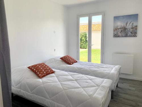two beds in a white room with a window at Villa Saint Mart in Saint-Martin-de-Ré