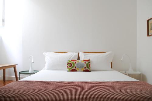 a bed with white sheets and a pillow on it at Alfama Prime Apartments by Homing in Lisbon