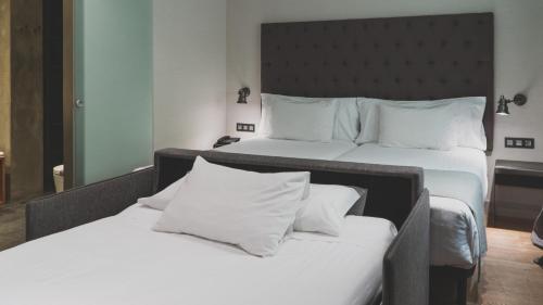 2 letti con cuscini bianchi in una camera d'albergo di Zenit Abeba a Madrid
