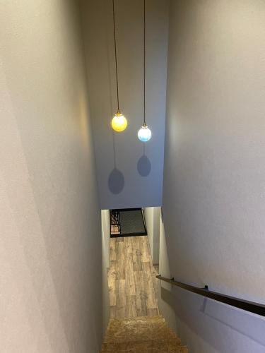 a hallway with two lights on the ceiling and a hallway with wood floors at COUSCOUS Glamping Manazuru in Manazuru
