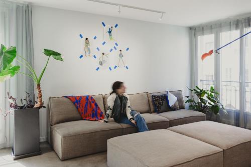 una mujer sentada en un sofá en una sala de estar en CHAMBRE ARTY CHEZ MINUIT DEUX, en Mâcon
