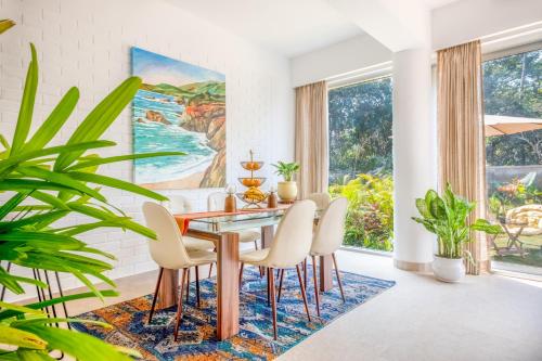 a dining room with a table and chairs and a painting at El Rocio Estate 2bhk in Assagao with Common pool, Free Parking,8 min away from Vagator in Assagao