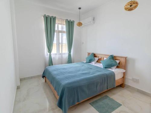 a bedroom with a bed with blue sheets and a window at Sunset Vista in Flic-en-Flac