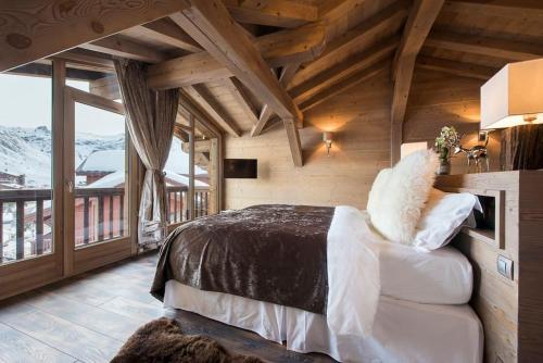 een slaapkamer met een bed en een groot raam bij Chalet Ambre in Tignes