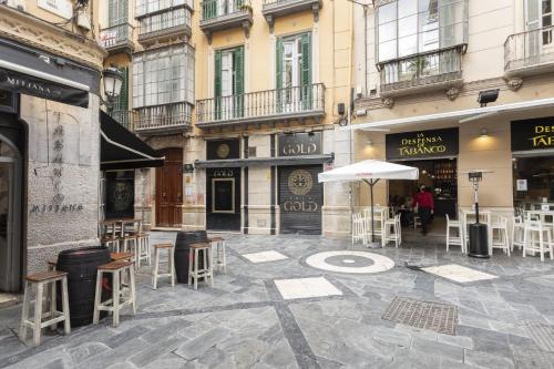 un patio con mesas, sillas y una sombrilla en Apartamentos Tribuna, en Málaga