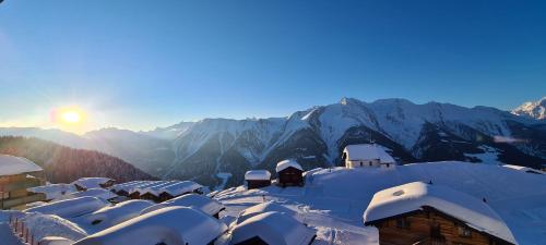 a snow covered village with mountains in the background at Imhof Alpine B&B Apartments in Bettmeralp