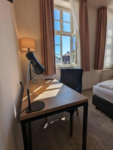 a desk with a lamp and a chair in a room at Hotel Fürstenhof in Büdingen