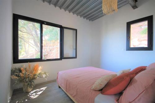 - une chambre avec un lit rose et 2 fenêtres dans l'établissement Fort Almanarre, à Hyères