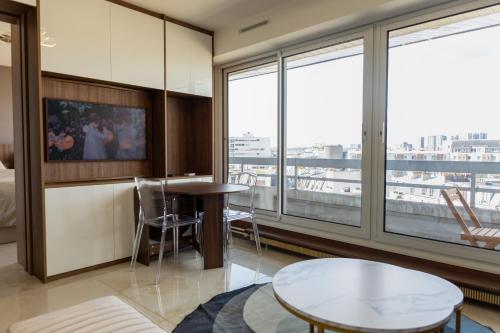 ein Hotelzimmer mit einem Tisch und einem großen Fenster in der Unterkunft Appartement Vue Tour Eiffel in Paris