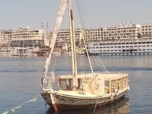 un voilier dans l'eau avec des bâtiments en arrière-plan dans l'établissement Nile Felucca Adventure, à Assouan